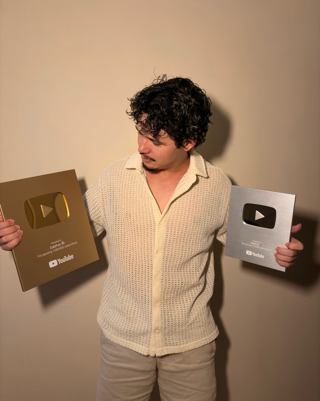 Gabriel Orofino segurando as placas do YouTube de 1 milhão e de 100 mil inscritos